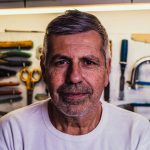 Portrait of a senior man with tools in the background, exuding confidence.
